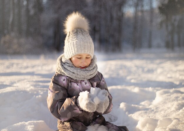 Kind, das mit Schnee im Winter spielt. Kinder fangen Schneeflocken