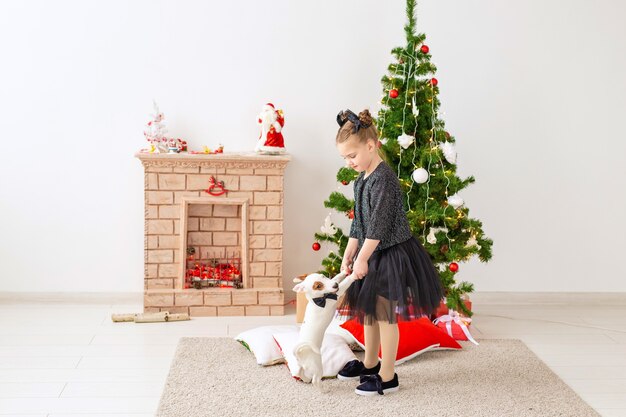 Kind, das mit welpen jack russell terrier nahe weihnachtsbaum spielt