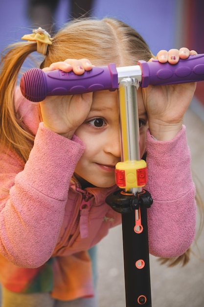 Foto kind, das neugierig und aufgeregt mit dem roller aussieht