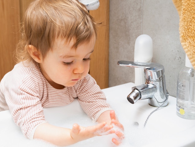 Kind, das seine Hände mit Seife und Wasser im Badezimmer wäscht