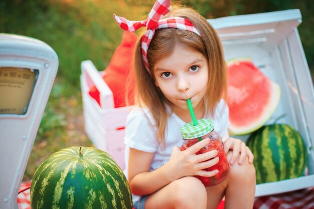 Kind, das Wassermelonenlimonade im Glas mit Eis und Minze als Sommer erfrischendes Getränk trinkt. Kalte alkoholfreie Getränke mit Obst