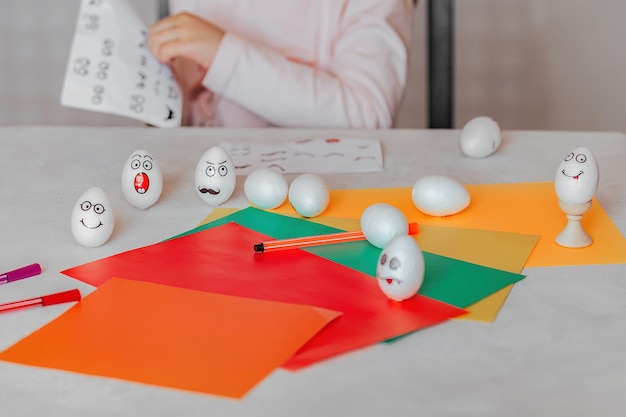 Kind dekoriert Eier mit emotionalen Aufklebern am Tisch