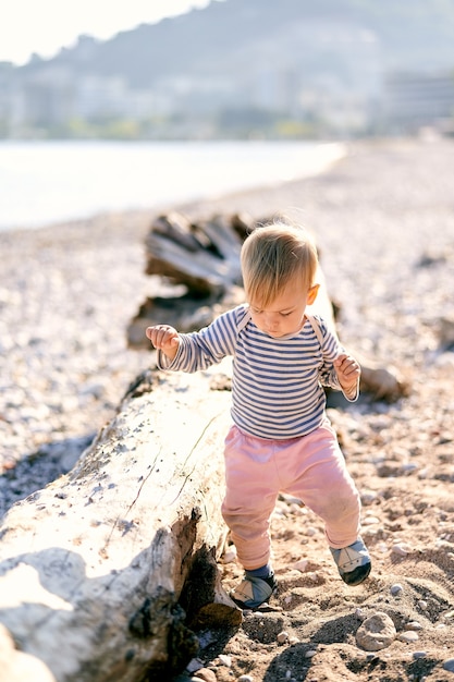 Kind geht in der Nähe von Treibholz am Strand