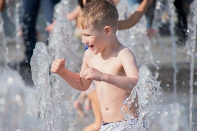 Foto kind genießt und kühlt sich im wasserstrahl ab close-up-porträt sonnenfoto hochwertiges foto