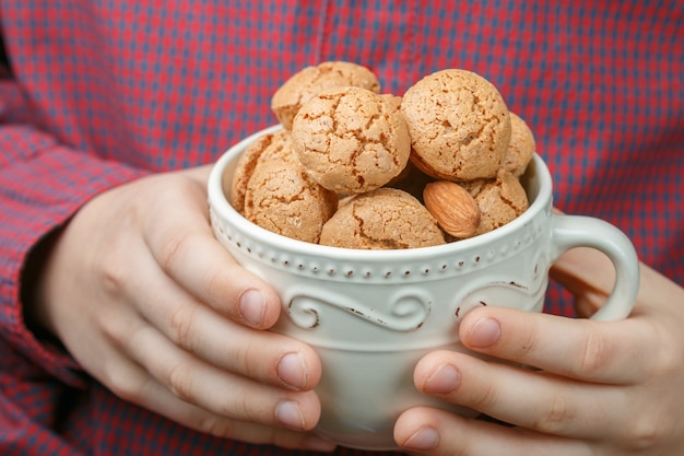 Kind hält eine Schale mit italienischem Mandelgebäck Amaretti. Knusprige Kekse.