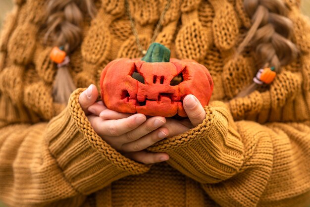 Kind hält einen kleinen kürbis für halloween