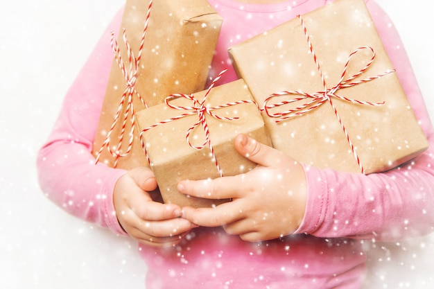 Kind hält einen Weihnachtsdekor und Geschenke auf einem weißen Hintergrund. Selektiver Fokus