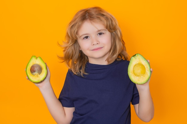 Kind hält rote Avocado im Studio Studioporträt eines süßen Kindes mit Avocado isoliert auf gelbem Hintergrundkopierraum