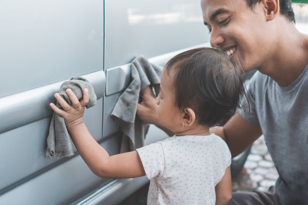 Kind hilft ihrem Vater, das Auto aufzuräumen