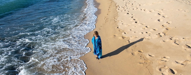 Kind im Handtuch zu Fuß am Sommerstrand.