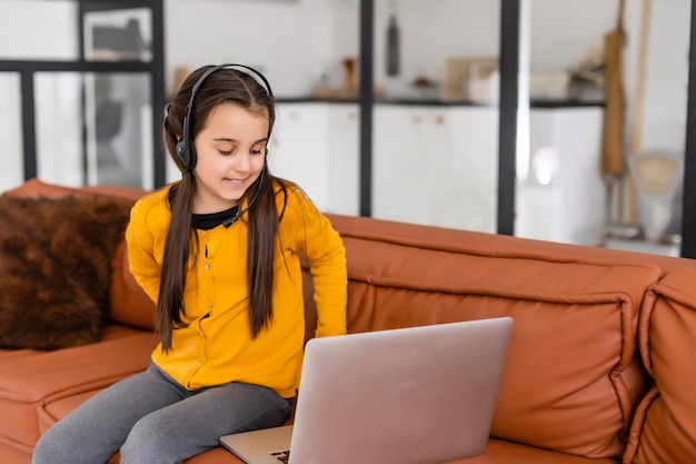 Kind im Internet. Ein kleines Mädchen nutzt einen Laptop-Video-Chat, um das Lernen zu kommunizieren, während es zu Hause an einem Laptop sitzt.