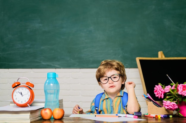 Kind im Klassenzimmer mit Tafel im Hintergrund zurück zum Schulkind von der Grundschule zuerst