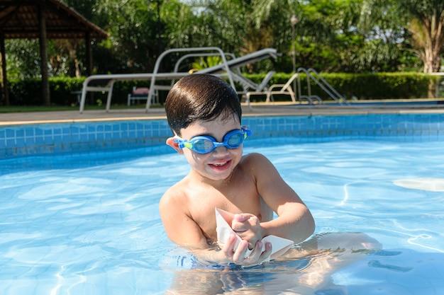 Kind im Pool zerstört das Papierboot mit der Faust.