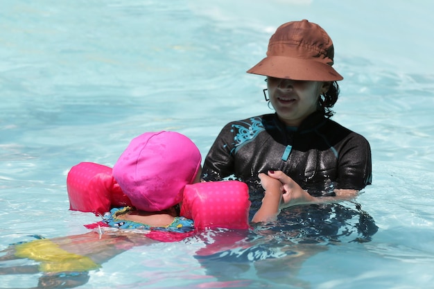 Kind im Poolschwimmen mit rosa Schwimmer mit blauem Wasser