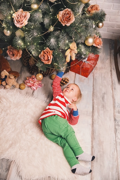 Kind im Pyjama verbringt Zeit mit der Familie zu Hause auf dem Hintergrund des Weihnachtsbaums