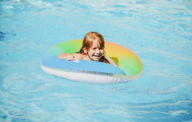 Kind im Schwimmbad entspannt schwimmen auf aufblasbarem Ring und hat Spaß im Wasser im Sommerurlaub gesund c