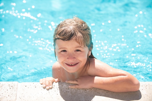 Kind im Sommerschwimmbad Kleiner Junge, der in den Sommerferien im Außenpool im Wasser spielt Kind, das lernt, im Außenpool zu schwimmen