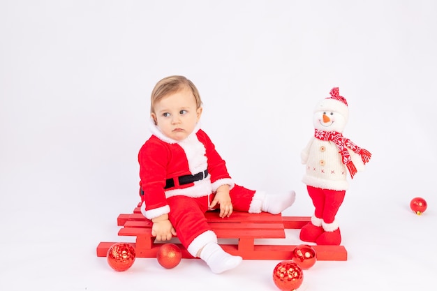 Kind im Weihnachtsmannkostüm auf rotem Schlitten