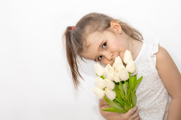 Kind im weißen Kleid, das einen Strauß Tulpen in ihren Händen hält, Platz für Textfrühlingskonzept