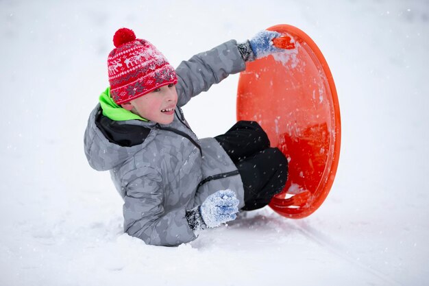 Kind im Winter Der Junge fährt Schlitten