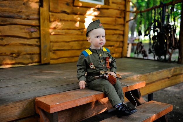 Kind in der Militäruniform gegen Naturhintergrund