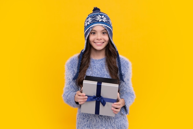 Kind in der Winterkleidung, die ein Geschenk für Neujahr oder Weihnachten hält. Glückliches Gesicht, positive und lächelnde Emotionen von Teenager-Mädchen