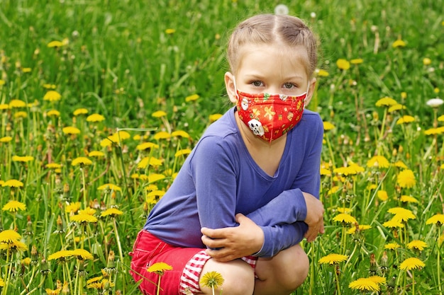 Kind in Maske auf Löwenzahnrasen