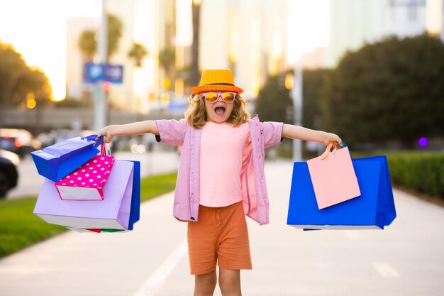 Kind in modischer Kleidung geht einkaufen Kind mit Einkaufspaketen Outdoor-Shopper Kind mit