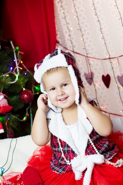 Kind in Neujahrskleidung, verbringt Zeit am Weihnachtsbaum