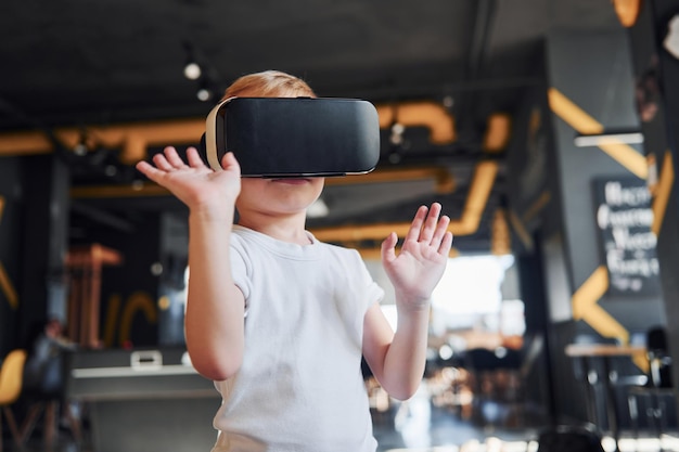 Kind in Virtual-Reality-Brille und Freizeitkleidung hat Spaß im Spielzimmer