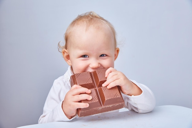 Kind isst ein großes Stück Schokolade. Das Konzept eines Junk-Food und einer gesunden Ernährung. Vegane Schokolade.