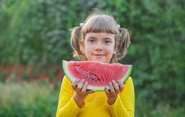 Kind isst eine Wassermelone im Garten