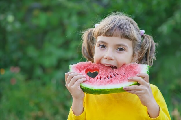 Kind isst eine Wassermelone im Garten