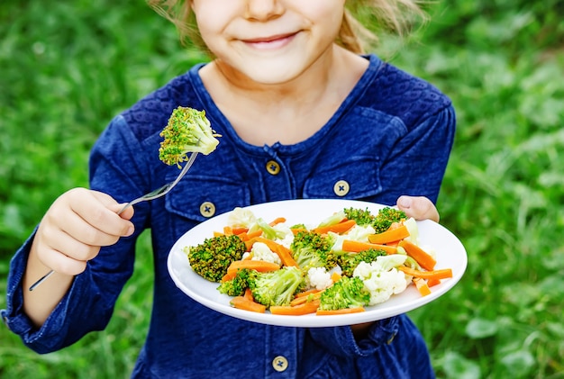 Kind isst Gemüse. Sommerfoto Selektiver Fokus