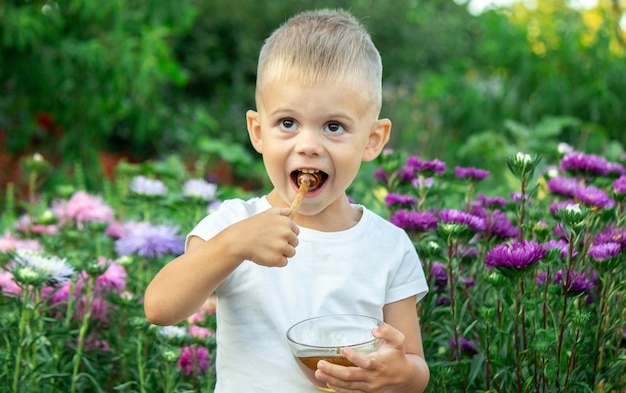 Kind isst Honig im Garten.