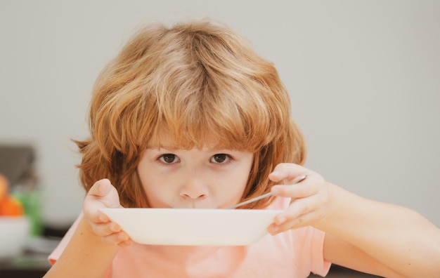 Kind isst Kleiner gesunder hungriger Junge, der Suppe mit Löffel isst Süßes, neugieriges, hungriges, lustiges Kind