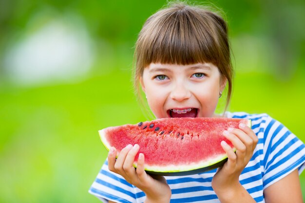 Kind isst Wassermelone Pre Teen Mädchen im Garten hält ein Stück Wassermelone glückliches Mädchen Kind ea...