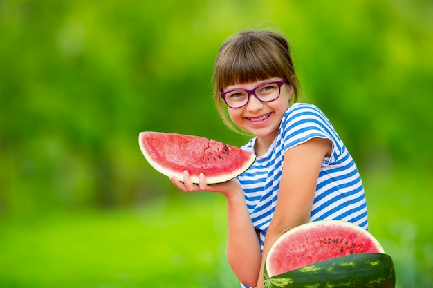 Kind isst Wassermelone Pre Teen Mädchen im Garten hält ein Stück Wassermelone glückliches Mädchen Kind ea...