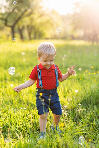 Kind Junge hat Spaß, in der Natur mit glänzenden Seifenblasen zu spielen