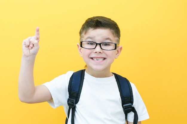 Kind Junge in Gläsern isoliert auf gelber Papierwand Tolle Idee Fröhlicher lächelnder Schuljunge geht zurück zur Schule Erfolgsmotivationssieger-Genie-Konzept