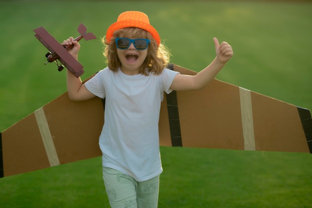 Kind, Junge, Kleinkind, das mit Spielzeugflugzeugflügeln spielt und Zukunft träumt Das Konzept der kindlichen Freundlichkeit und Kindheit Kinder laufen mit dem Flugzeug auf dem Feld