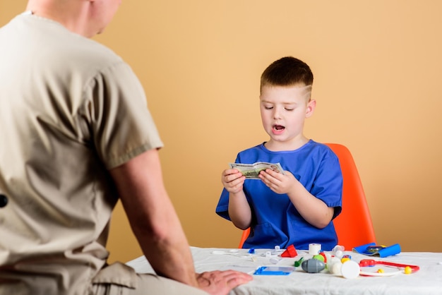 Kind, kleiner Arzt, sitzt am Tisch, medizinische Instrumente, Gesundheitswesen, Kinderarzt-Konzept, Junge, süßes Kind und sein Vater, Arzt, ärztliche Untersuchung, Kinderbetreuung, Kindergarten, Krankenhausangestellter, medizinischer Dienst