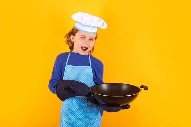 Kind-Koch-Koch mit Kochpfanne Kochen von Kindern Chef-Kind-Junge, der gesundes Essen macht Porträt des kleinen Kindes in Kochmütze auf Studiohintergrund isoliert Kid-Chef Kochprozess