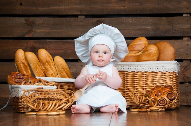 Kind kocht ein Croissant im Hintergrund von Körben mit Brötchen und Brot