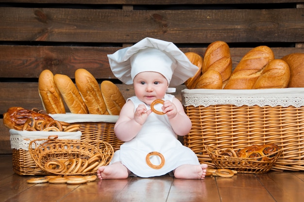 Kind kocht ein Croissant im Hintergrund von Körben mit Brötchen und Brot