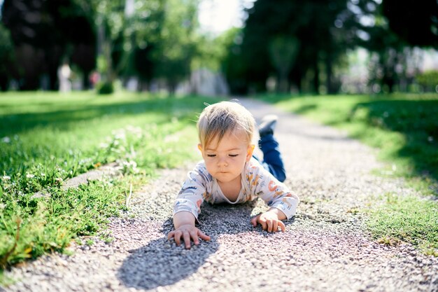 Kind liegt auf dem Bauch auf dem Weg im Park