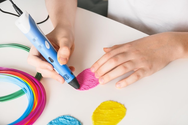 Kind macht Ostereier mit 3D-Stift Kunststofffäden auf weißem Hintergrund Nahaufnahme