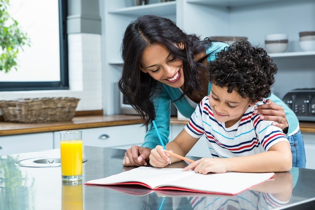 Kind mãe ajudando seu filho a fazer lição de casa