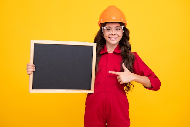 Kind Mädchen Builder in Hard Hat Helm Teenager-Mädchen Arbeiter halten Tafel isoliert auf gelbem Hintergrund Kinder Renovierungskonzept Copy Space Mock-up