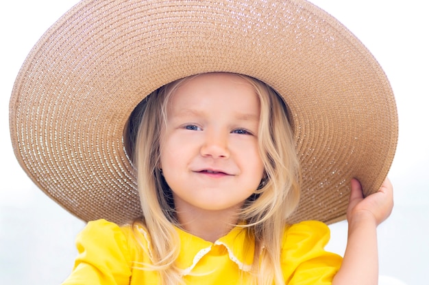 Kind Mädchen in einem Strohhut in gelben Kleidern